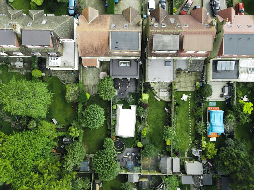 An aerial view of several terraced gardens in Tower Hamlets, showcasing a variety of lush green lawns, mature trees, and neatly maintained flowerbeds. The gardens feature different layouts with some h